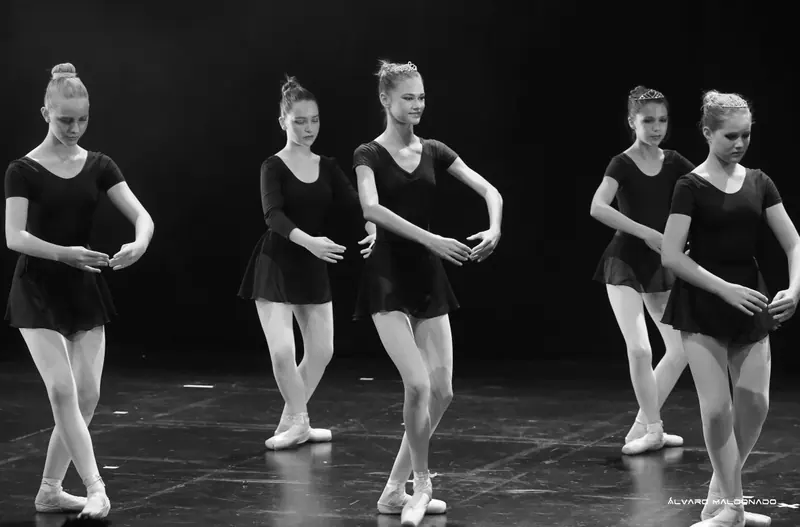 Cliché noir et blanc de danseuses adolescentes en justaucorps et jupettes noirs, sur pointes, mains basses