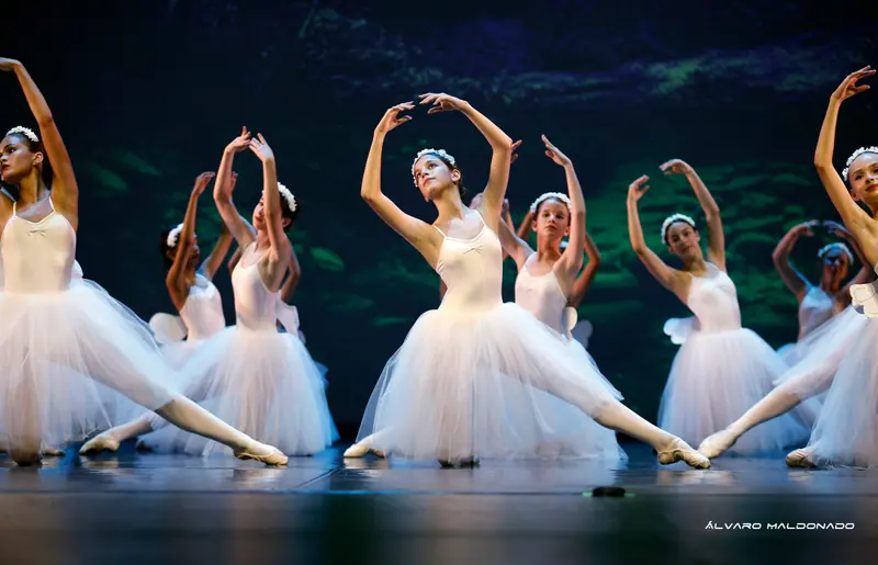 Danseuses en tutus romantiques blancs et couronnes de fleurs en fente basse, une jambe tendue, bras arrondis au-dessus de la tête