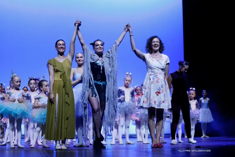 Trois femmes souriantes lèvent les mains jointes pour le salut, l'une en costume de chat gris, les fillettes costumées derrière