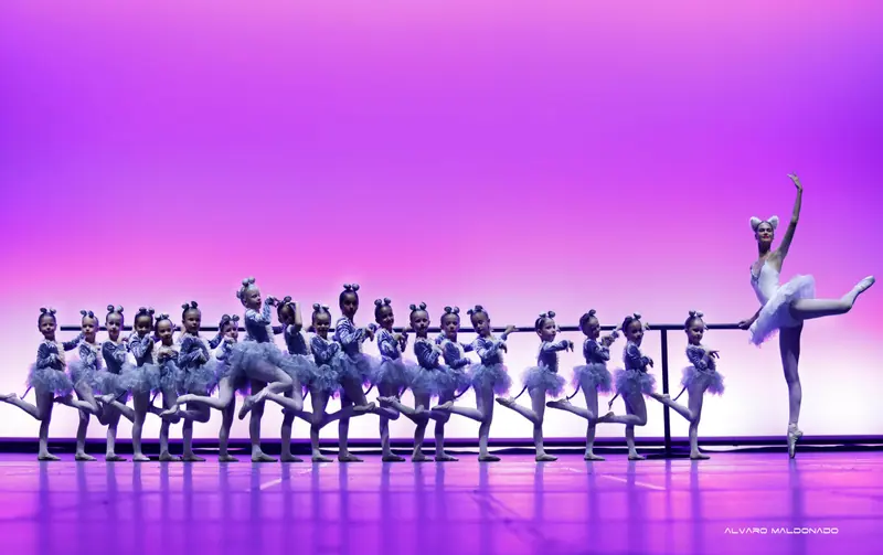 Une longue rangée de fillettes en tutus gris de souris lève la jambe à la barre tandis qu'une ballerine aux oreilles de chat tient un arabesque
