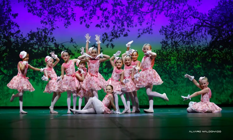 Fillettes en robes roses à motif de roses, gants de dentelle blancs et petits chapeaux posent avec espièglerie sur fond vert et violet
